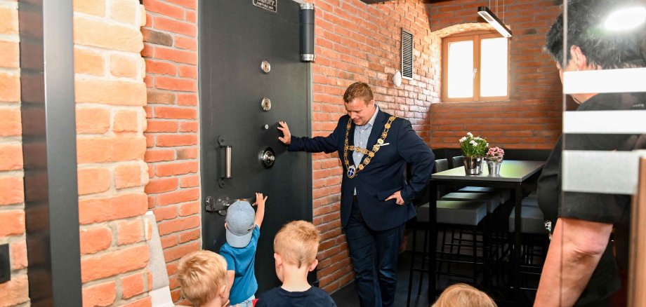 Bürgermeister Benjamin Tschesnok zeigt Kindern den Tresor im Rathaus