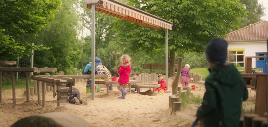 Kinder spielen im Außenbereich der Kita Buchfinkenland in Michelsrombach im Sandkasten